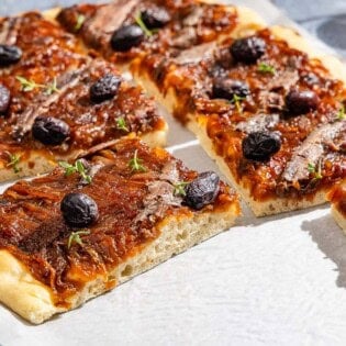 Sliced Pissaladière on parchment paper.