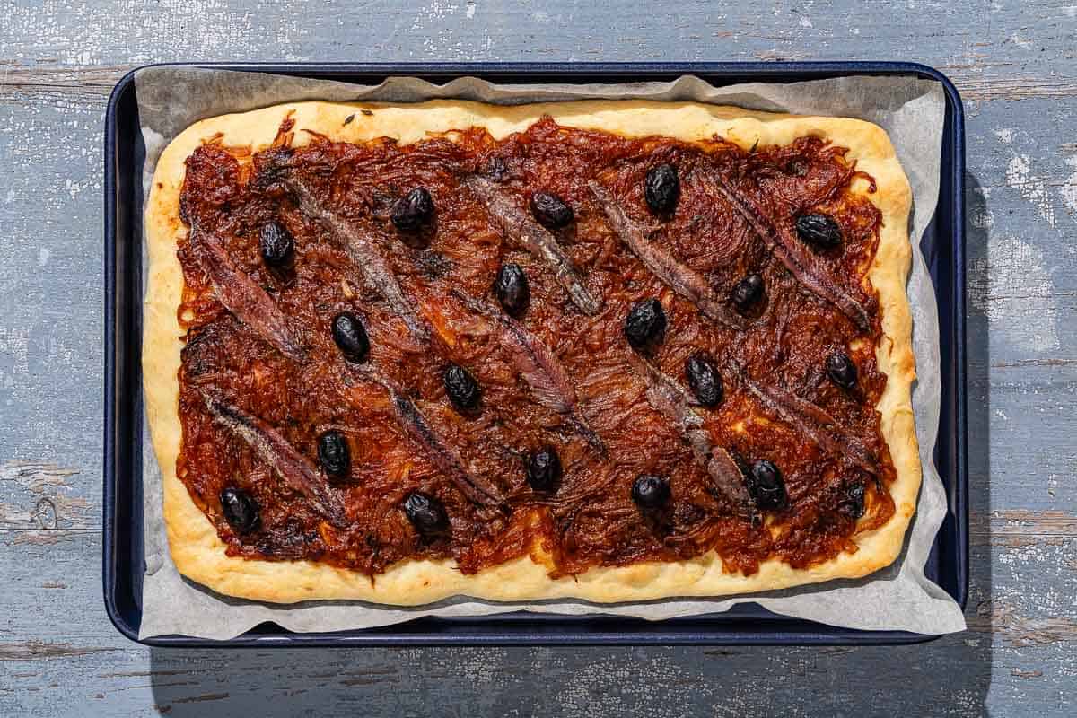 Baked pissaladière on a parchment lined sheet pan.