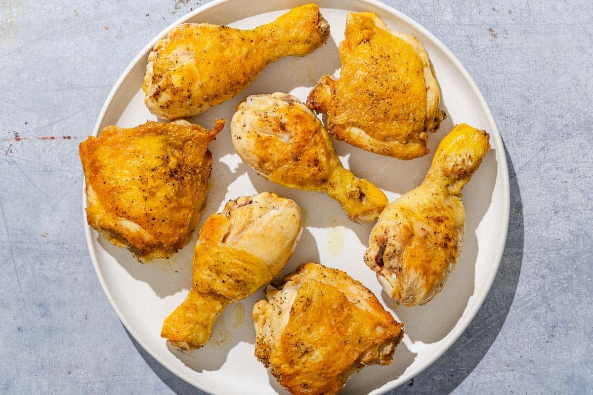 The browned pieces of chicken for the chicken and peppers on a plate.
