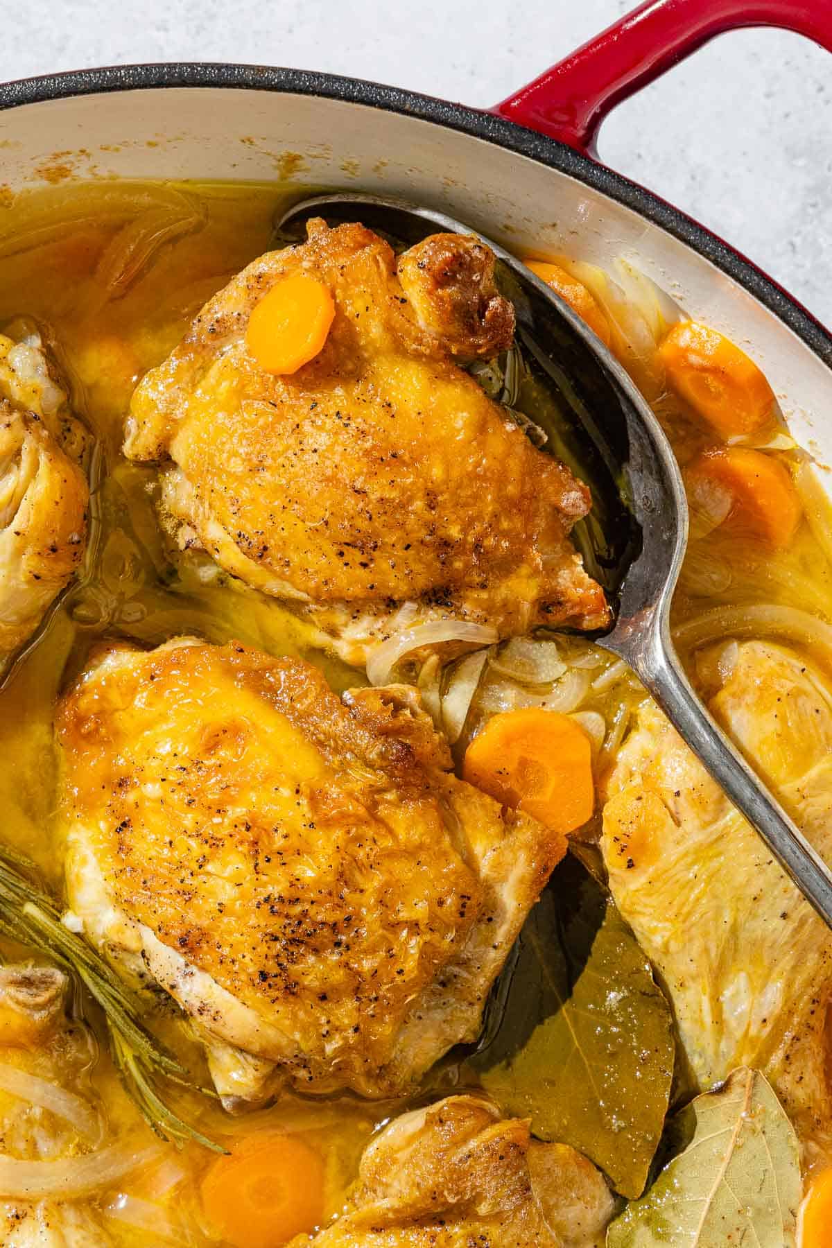 Escabeche de pollo in a skillet with a serving spoon.