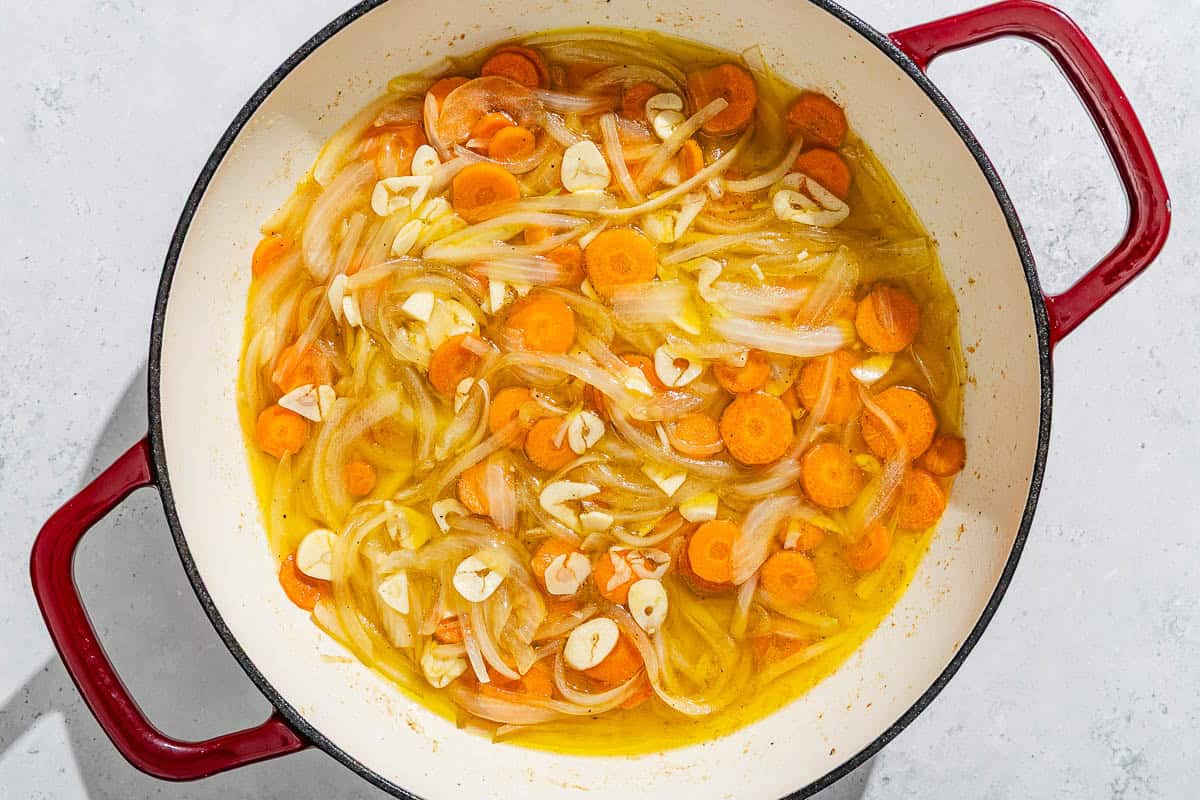 The vegetables for the escabeche de pollo cooking in a skillet.