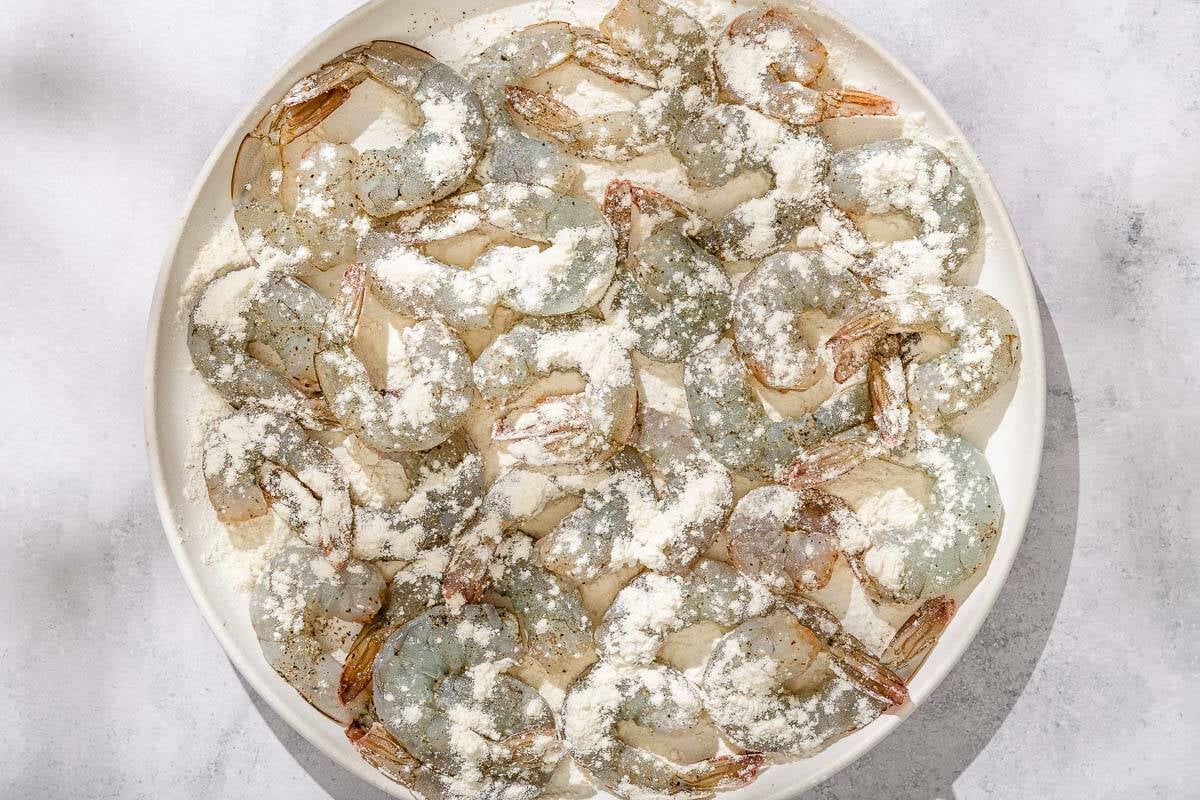 The raw shrimp for the shrimp piccata on a platter just after being sprinkled with the flour.