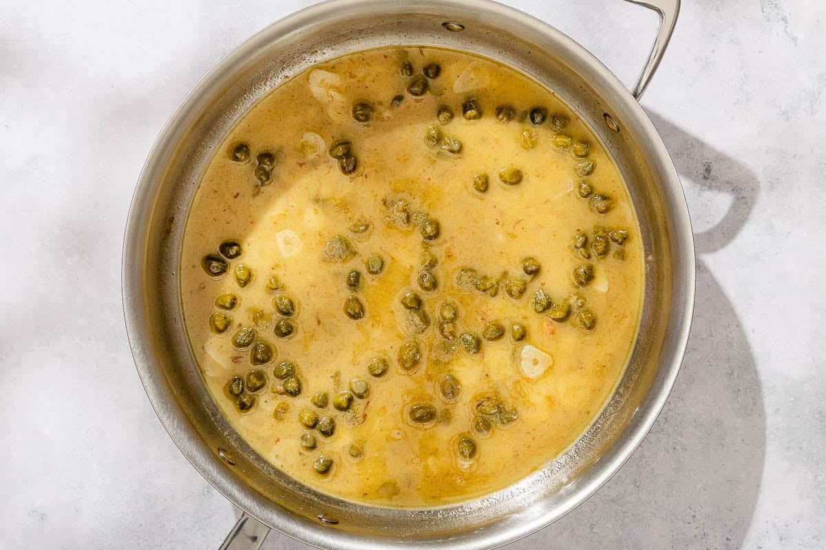 The sauce for the shrimp piccata simmering in a skillet.