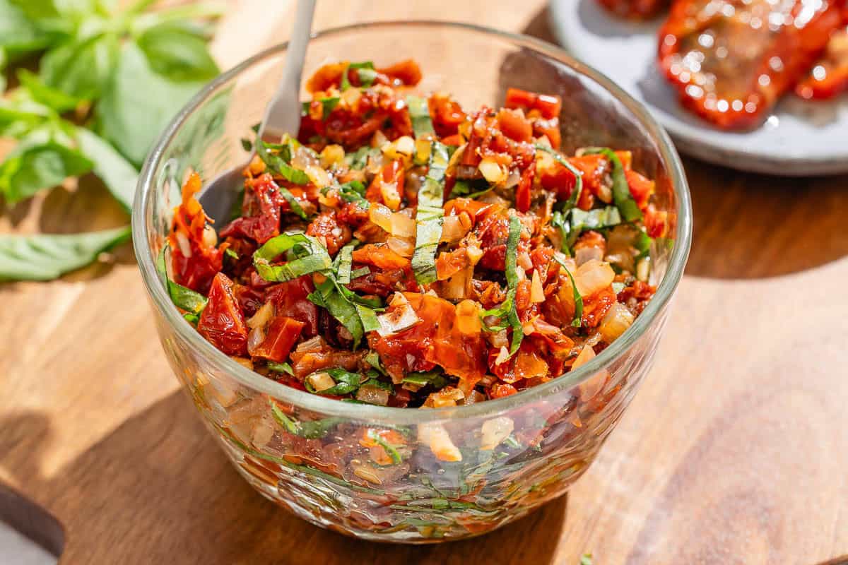 Sun dried tomato salsa in a bowl with a spoon.
