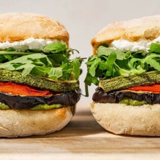 Two roasted vegetable sandwiches sitting side-by-side.