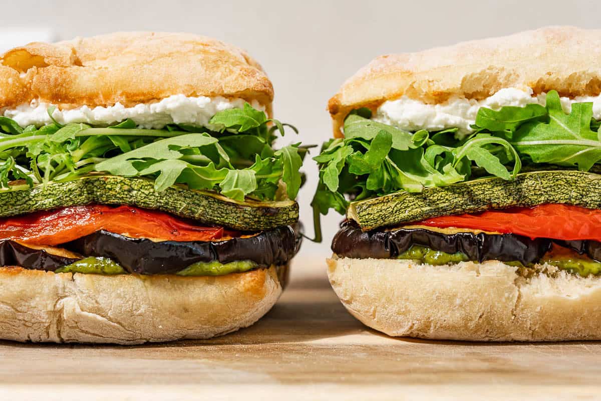 Two roasted vegetable sandwiches sitting side-by-side.