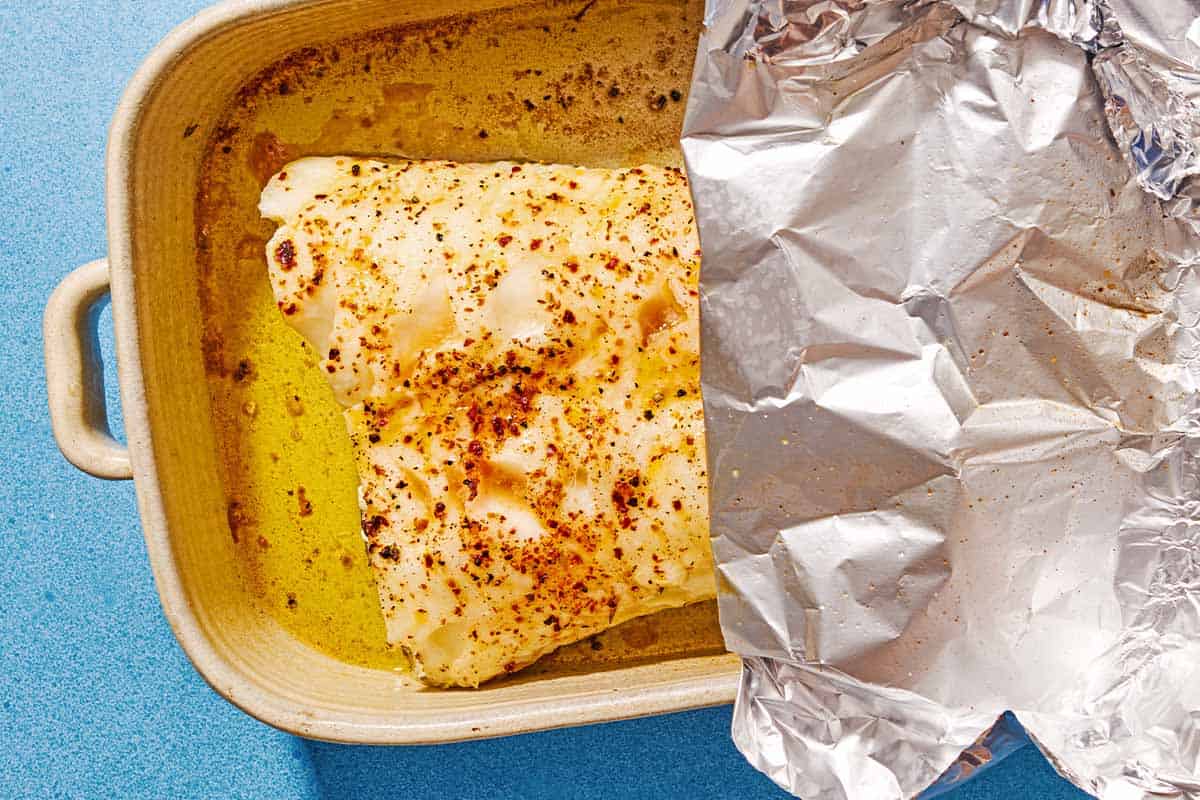 The baked sea base in a baking dish partially covered with foil.