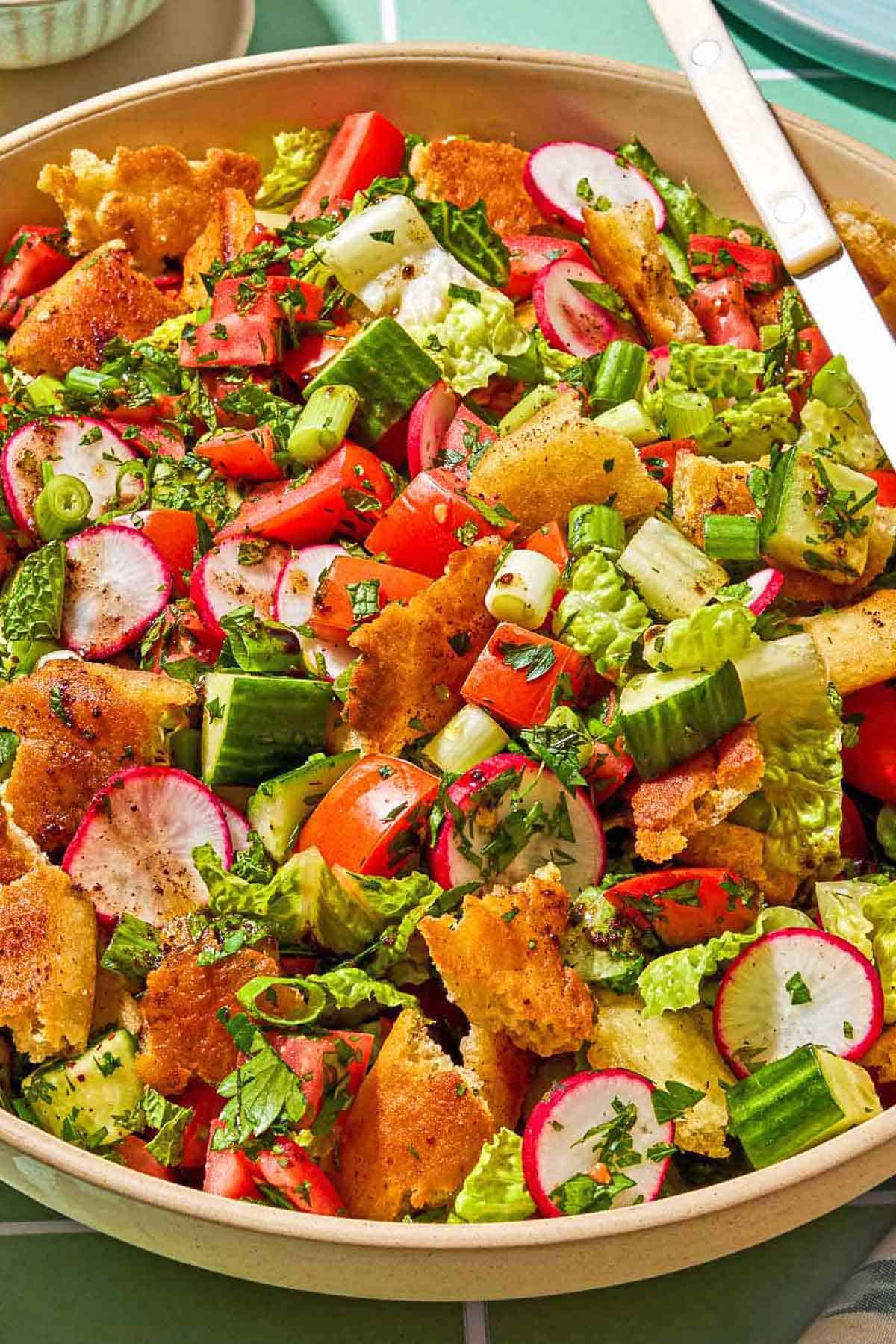 Fattoush in a serving bowl with a spoon.