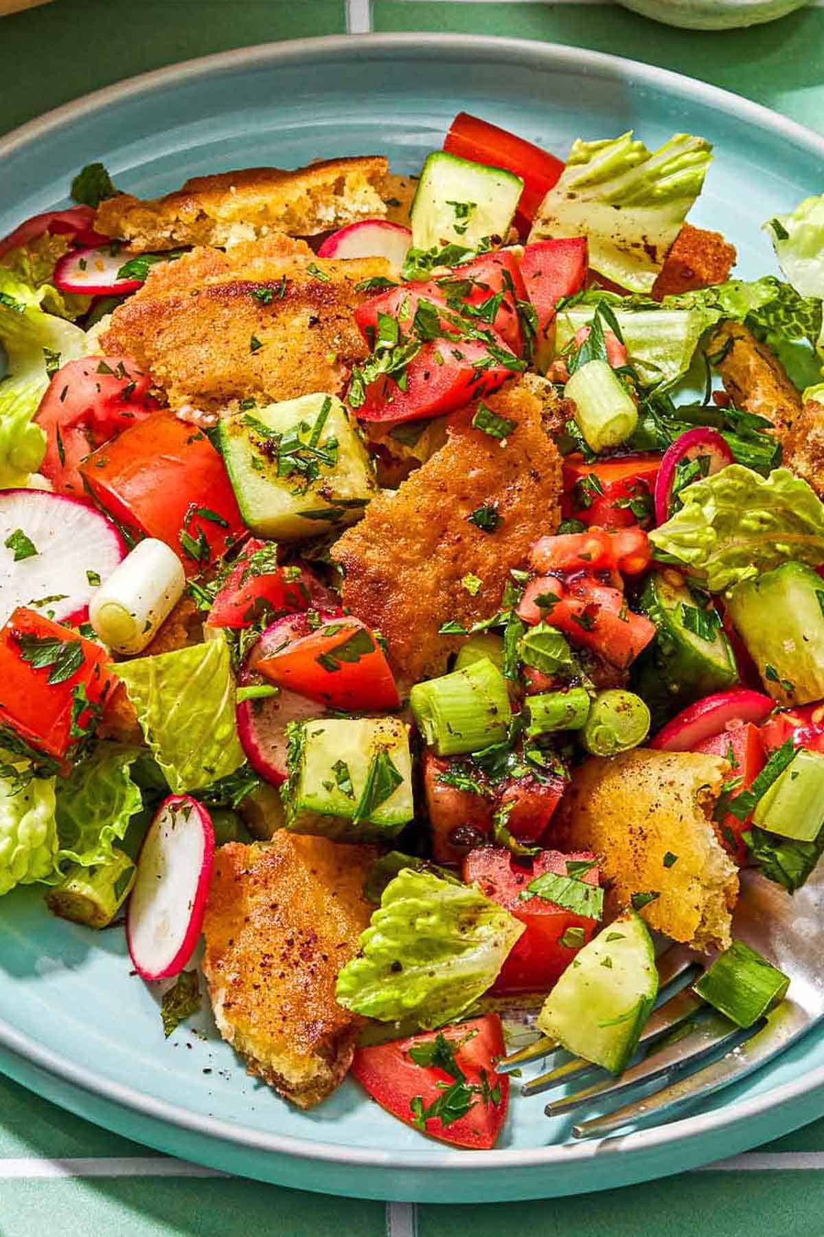 A serving of fattoush salad on a plate with a fork.