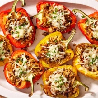 Several grilled stuffed peppers on a serving platter.