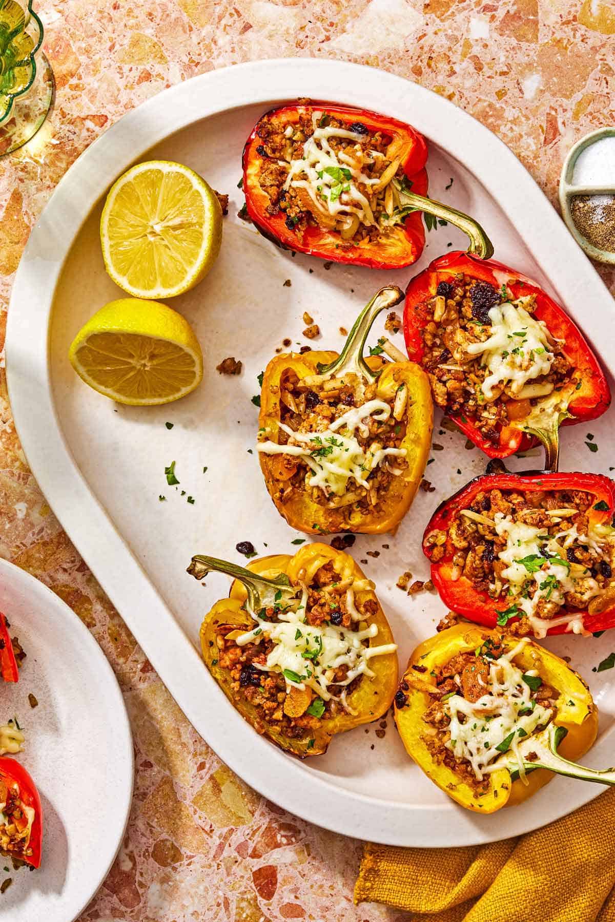 Several grilled stuffed peppers on a serving platter with 2 lemon halves.