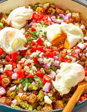Potato hash with asparagus, chickpeas and feta in a skillet with a wooden spoon.