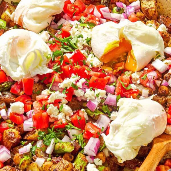 Potato hash with asparagus, chickpeas and feta in a skillet with a wooden spoon.