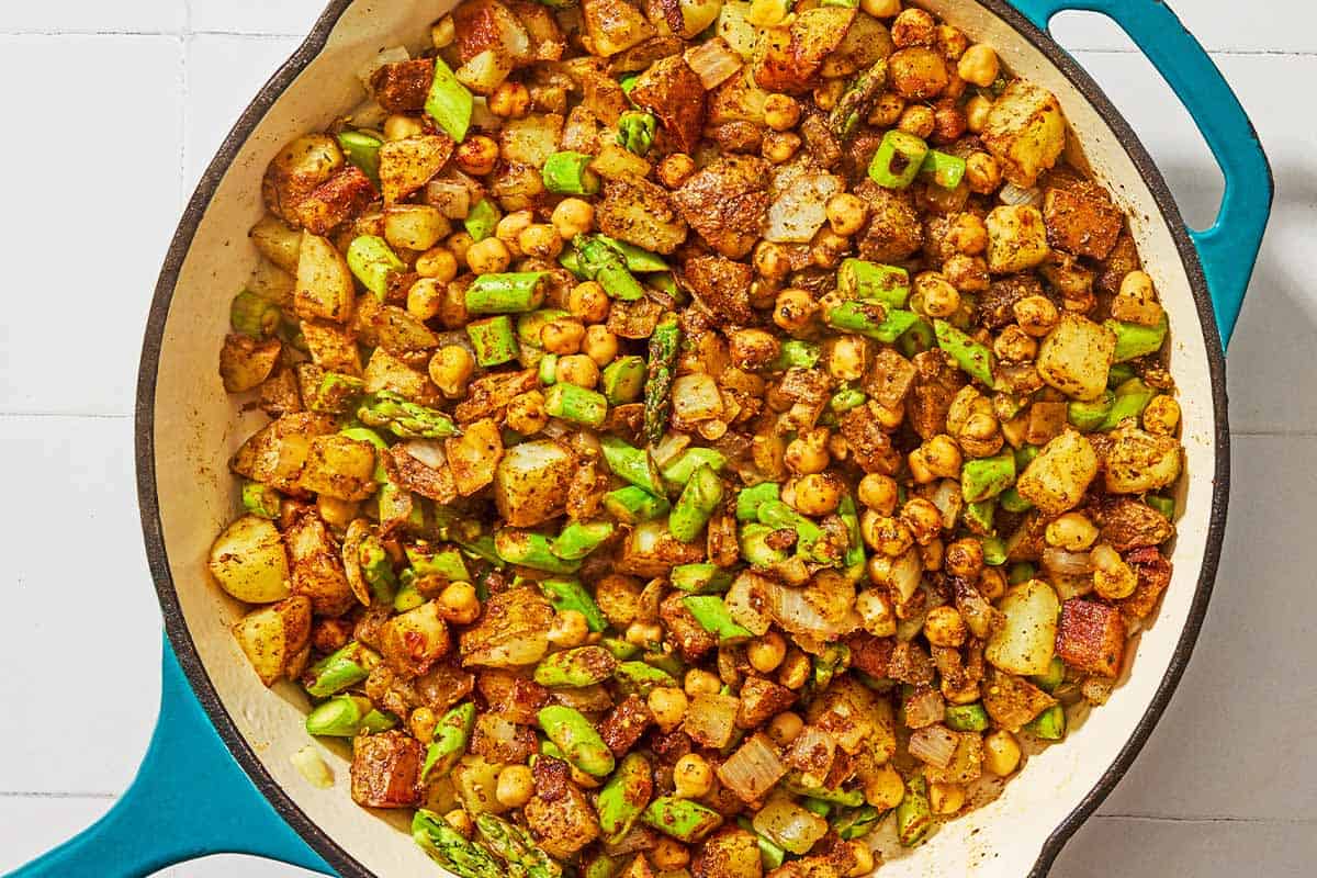 The vegetables for the potato hash being cooked in a skillet.