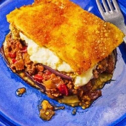 A serving of moussaka on a plate with a fork.