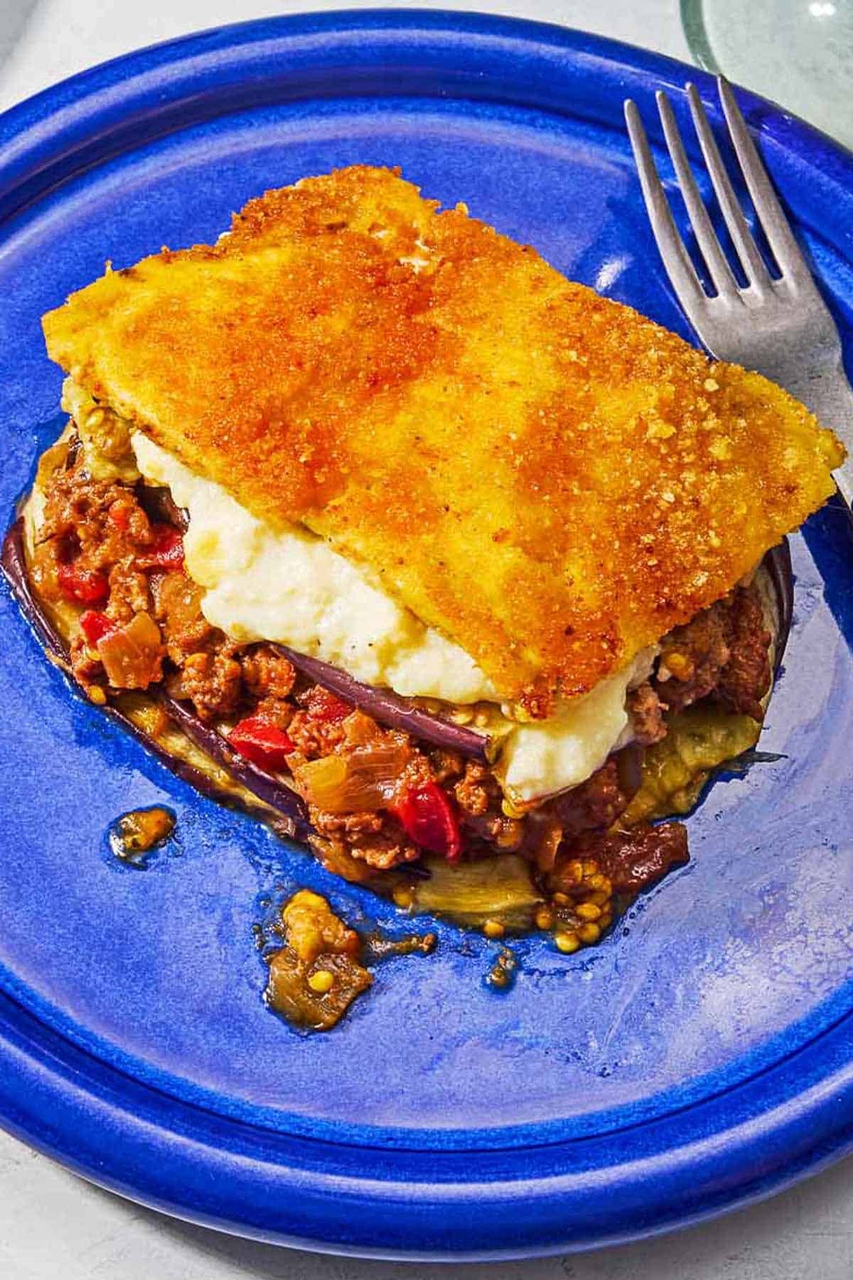 A serving of moussaka on a plate with a fork.
