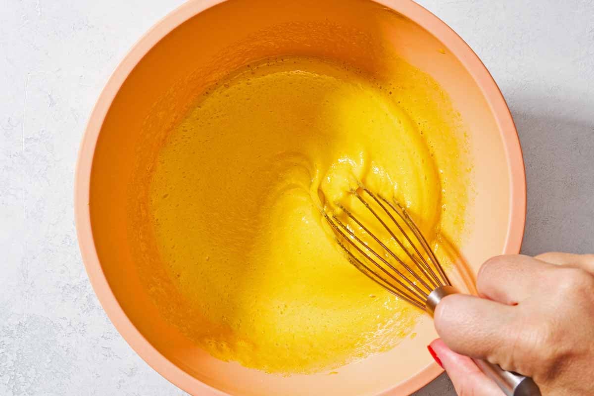 The egg yolks and sugar for the persian ice cream being stirred together with a whisk.