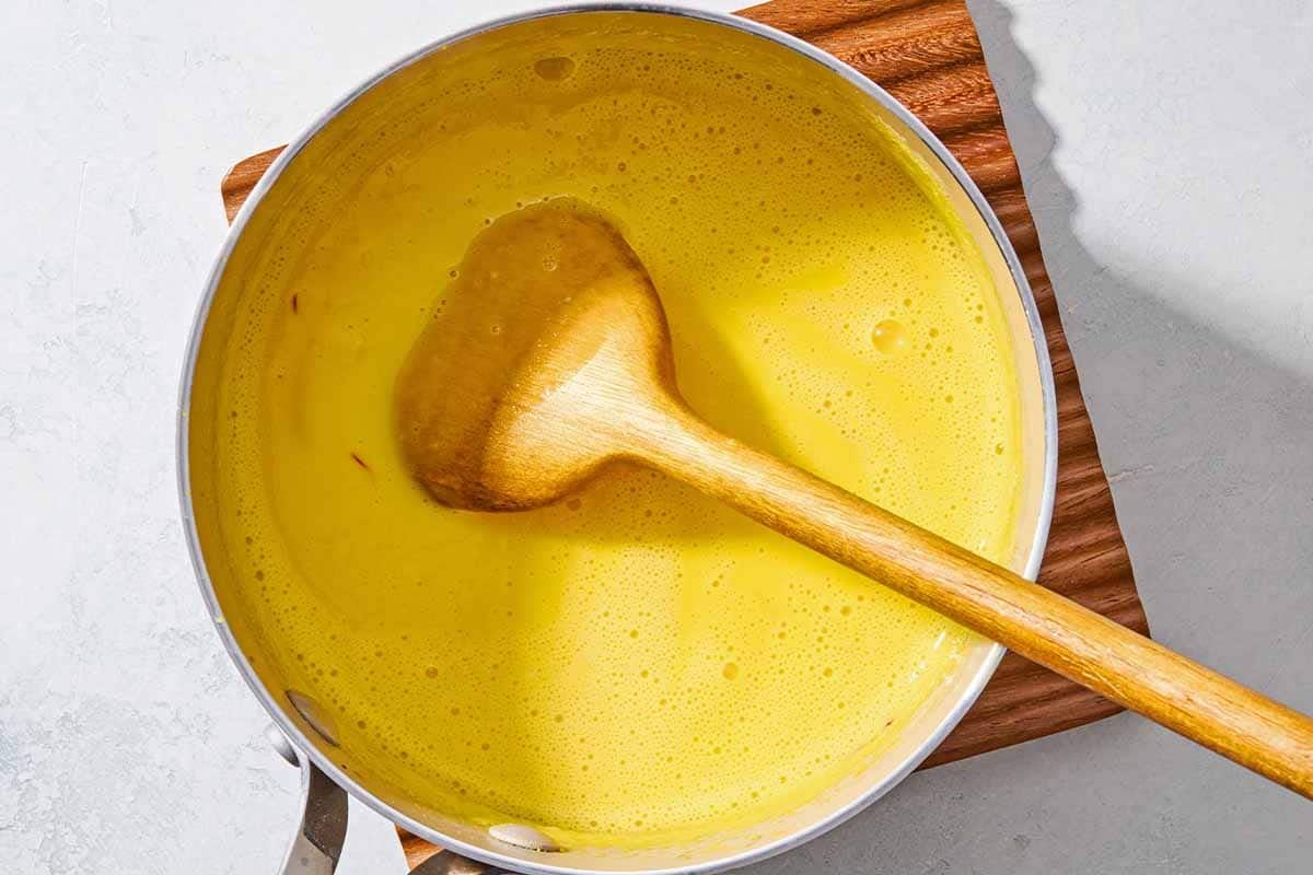 The milk for the persian ice cream flavored with the saffron, a pinch of salt and some sugar in a saucepan with a wooden spoon.
