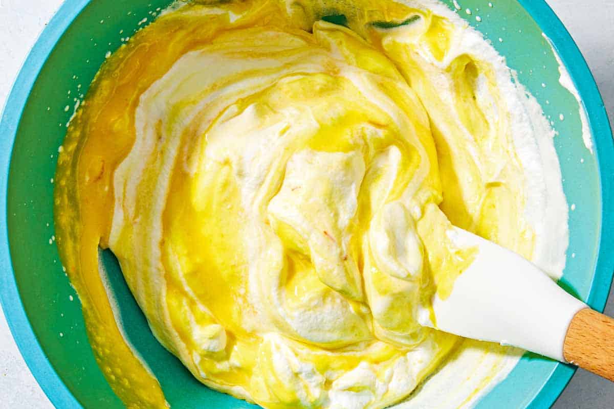 The custard for the persian ice cream being combined with the whipped cream in a bowl with a spatula.