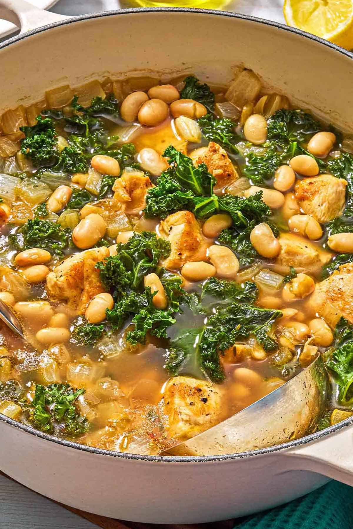 White bean and kale soup in a pot with a ladle.