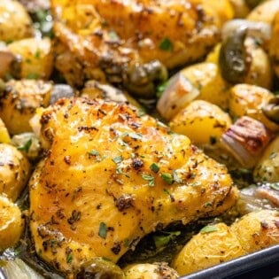 A close up of the baked chicken and potatoes recipe on a sheet pan.