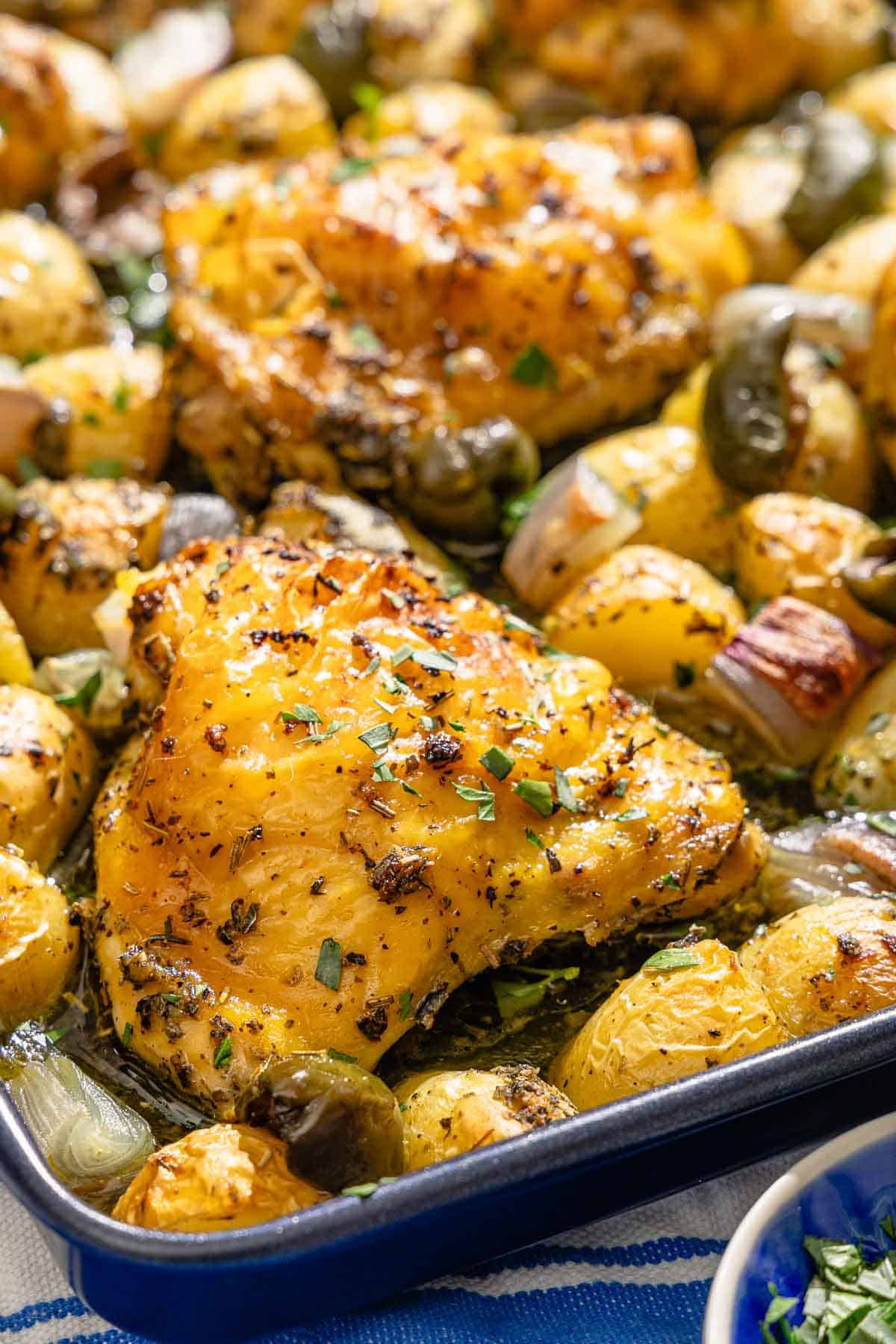 A close up of the baked chicken and potatoes recipe on a sheet pan.