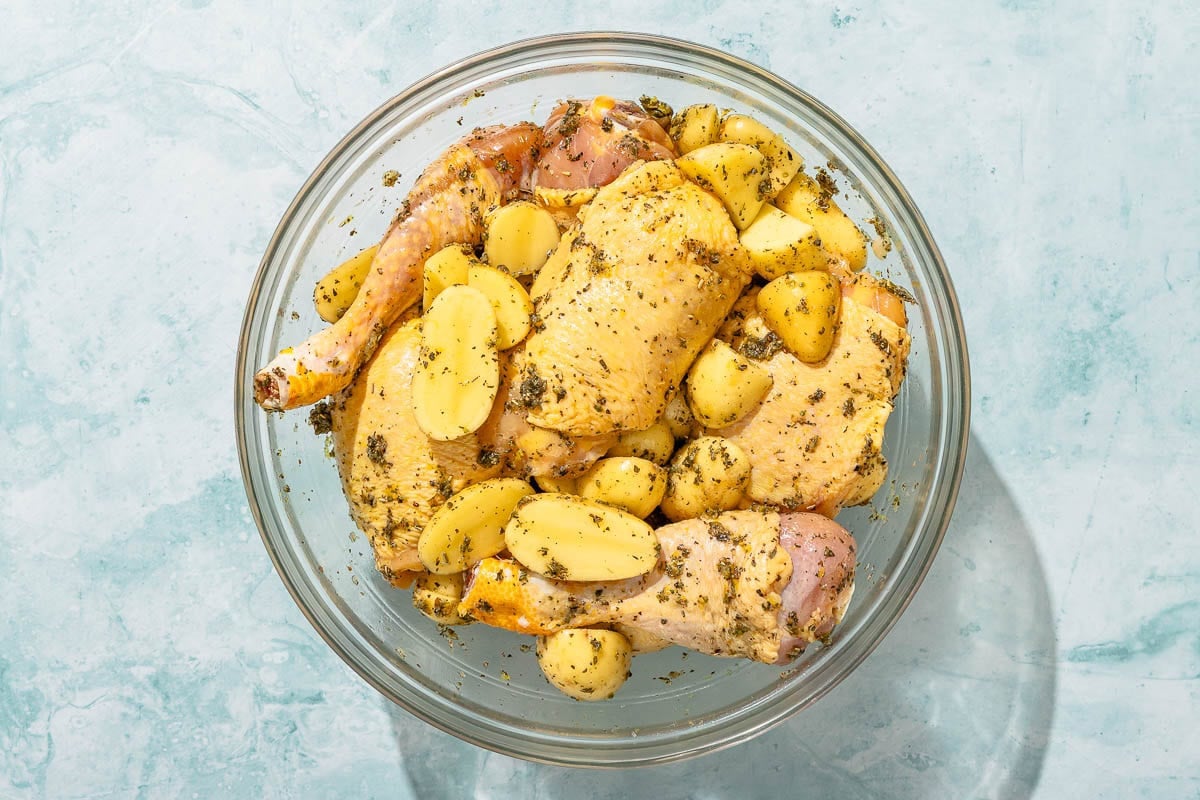 The ingredients for the chicken and potatoes recipe marinating in a large bowl.