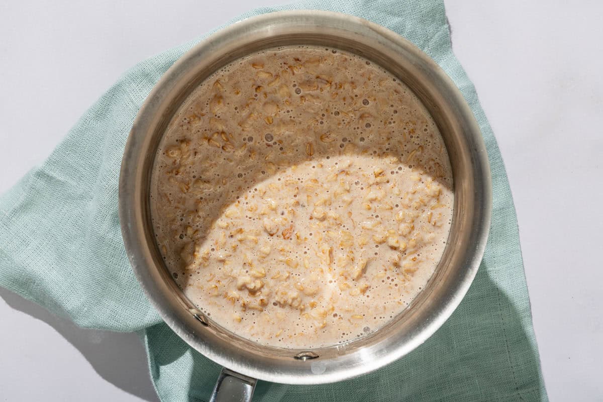 Oatmeal in a saucepan resting on a cloth napkin.