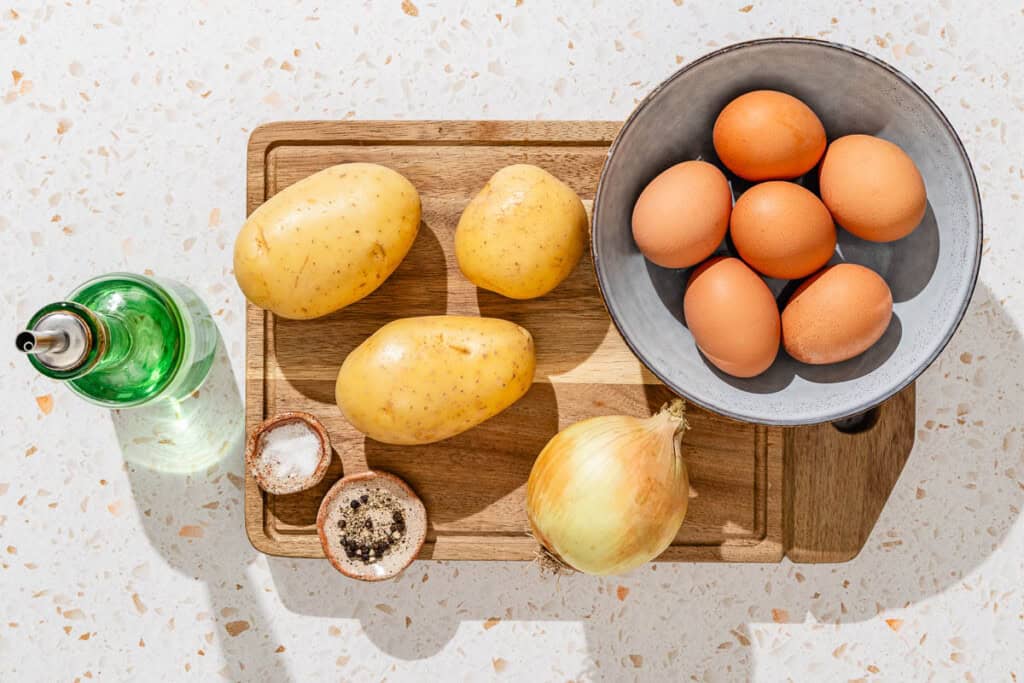 Ingredients for spanish tortilla including eggs, potatoes, onion, olive oil, salt, and black pepper.