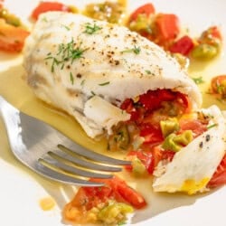 A close up of a stuffed flounder fillet on a plate with a fork.