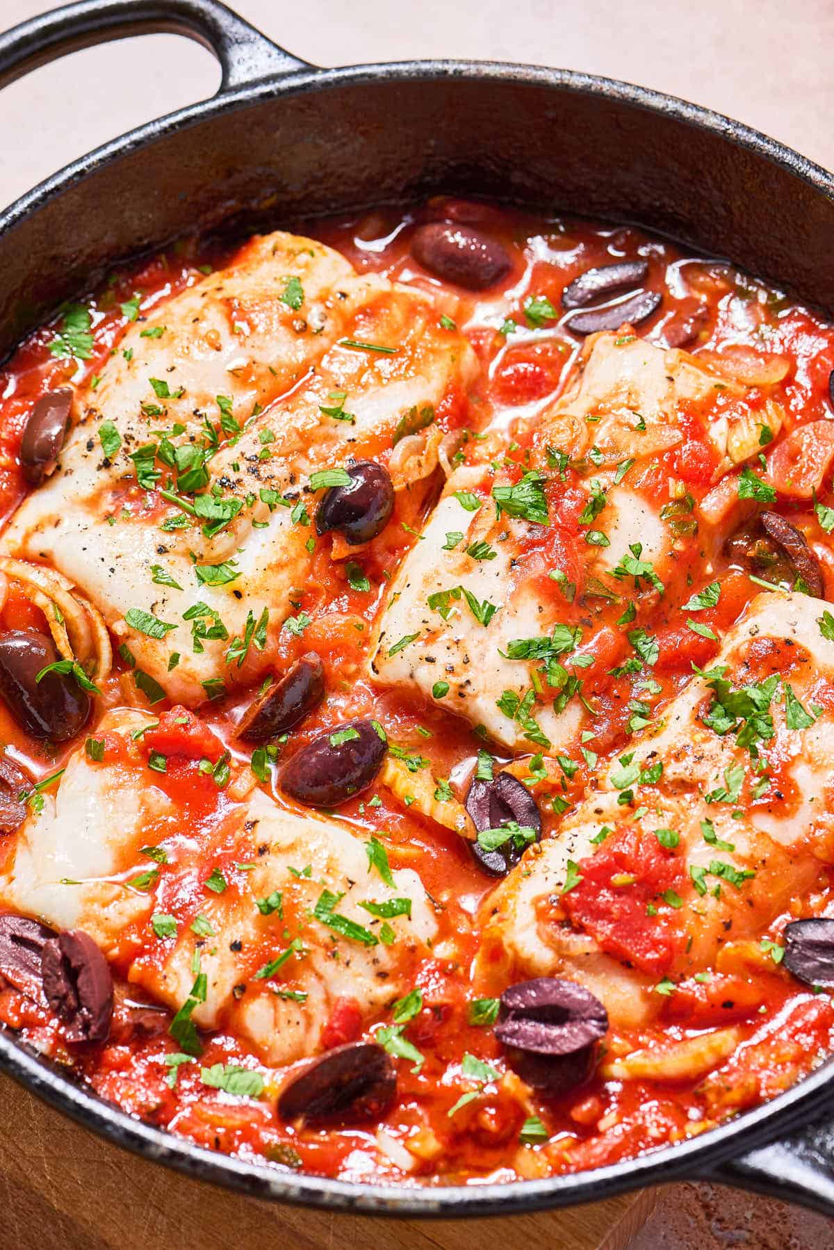 A close up of provençal fish in a cast iron skillet.