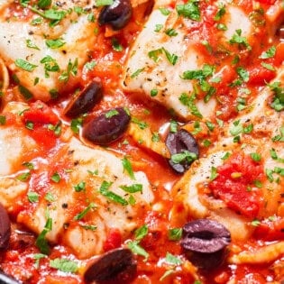 A close up of provençal fish in a cast iron skillet.
