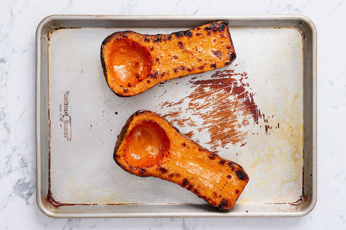 Two roasted butternut squash halves on a sheet pan.
