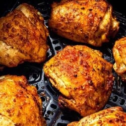 Six air fryer chicken thighs in an air fryer.