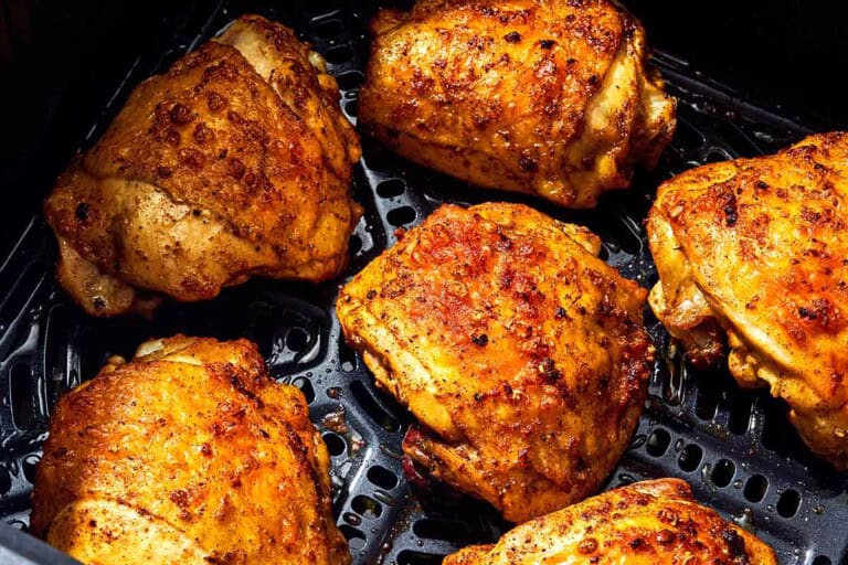 Six air fryer chicken thighs in an air fryer.