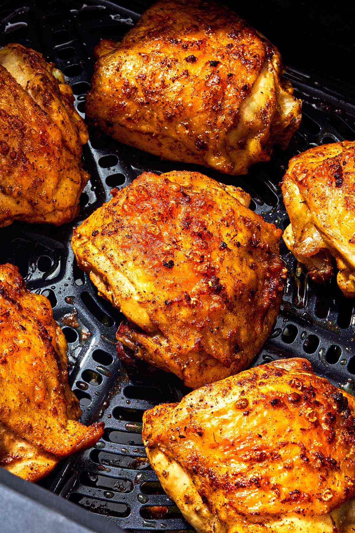 Six air fryer chicken thighs in an air fryer.