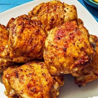 Six air fryer chicken thighs on a plate.