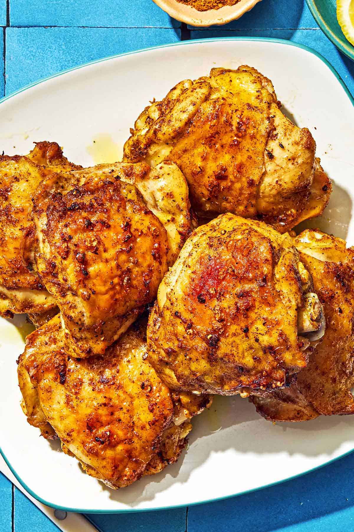 Six air fryer chicken thighs on a plate.