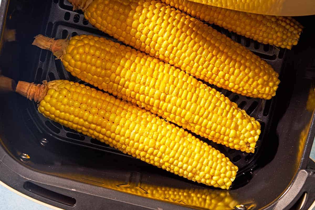 4 ears of corn in the pan of an air fryer.