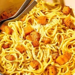 Butternut squash pasta in a pot with serving utensils.