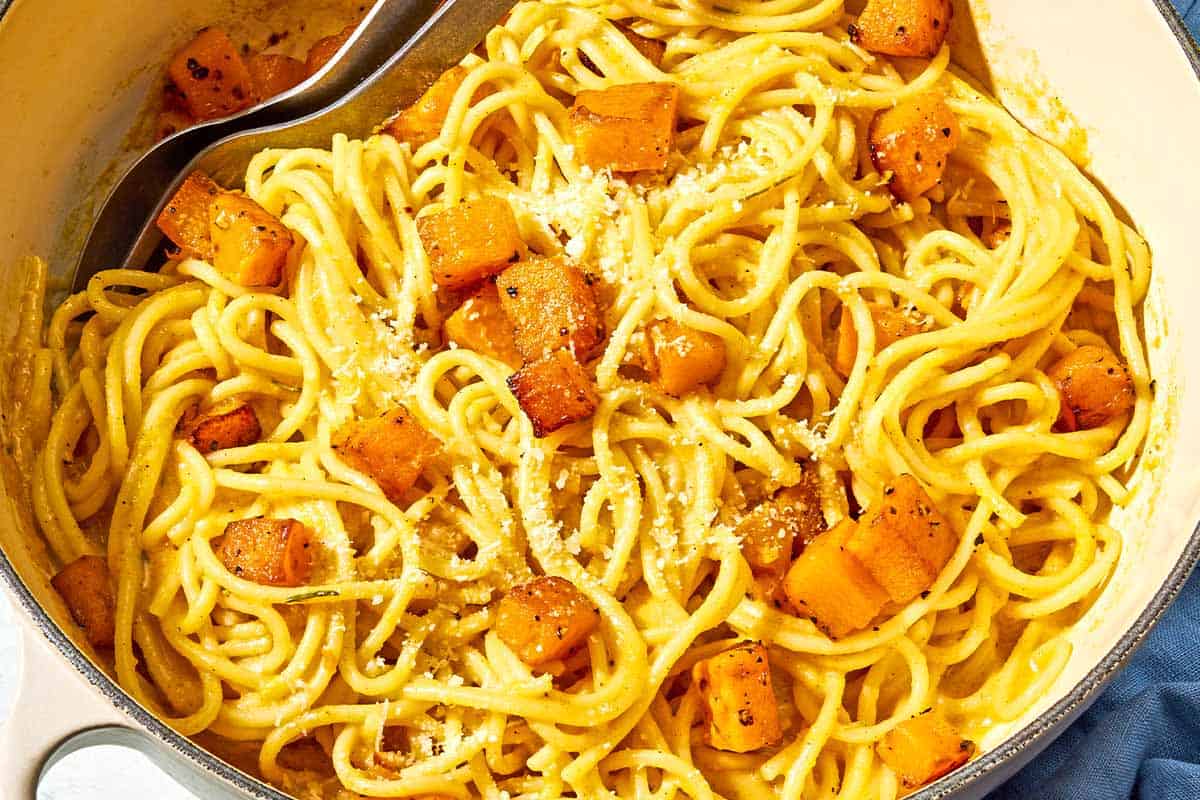 Butternut squash pasta in a pot with serving utensils.