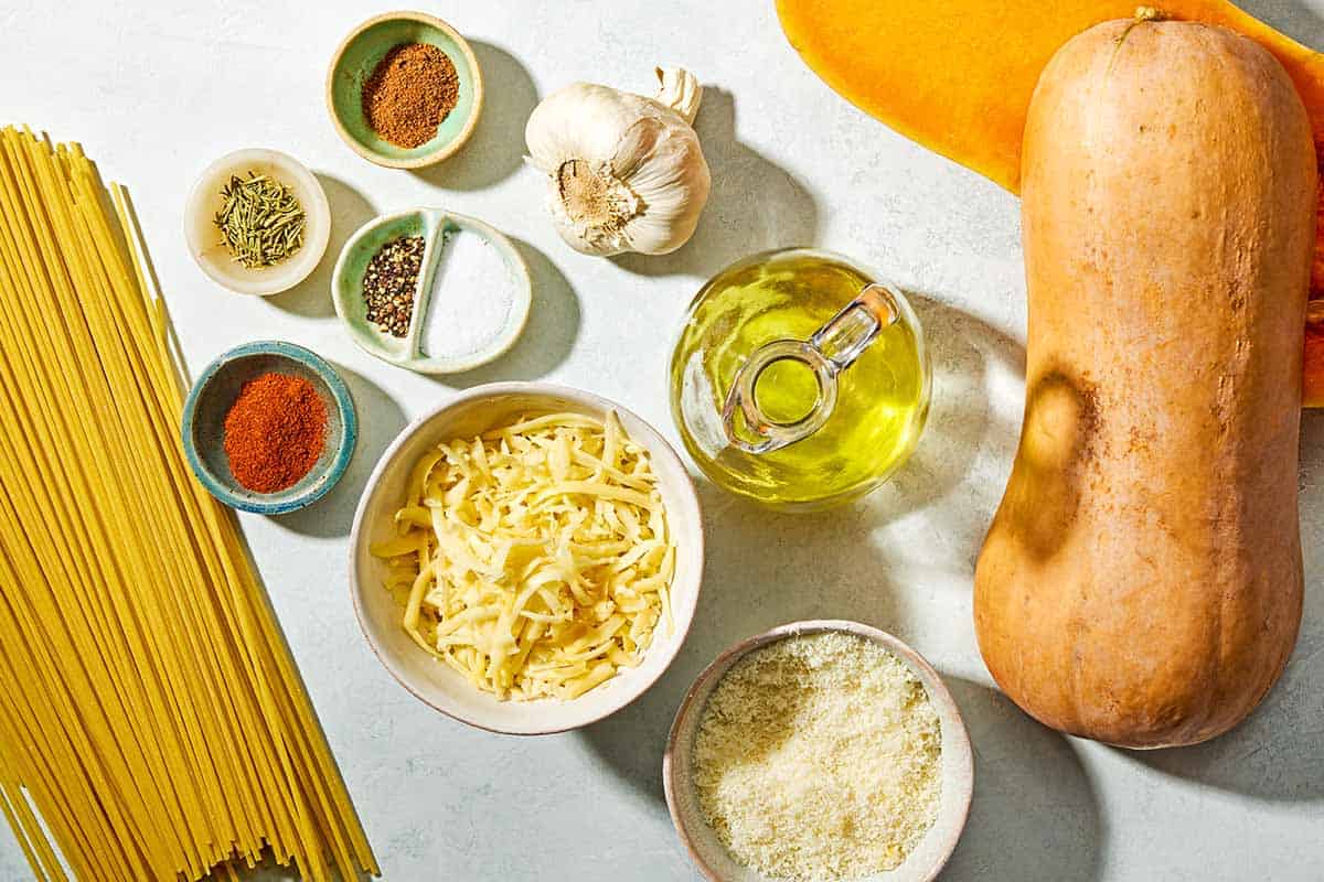 Ingredients for butternut squash pasta including butternut squash, salt, black pepper, olive oil, garlic, spaghetti, dried rosemary, nutmeg, sweet paprika, grated pecorino romano cheese, grated gruyere cheese.