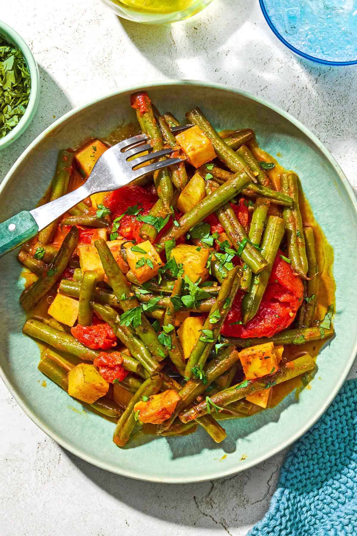 A serving of fasolakia on a plate with a fork.