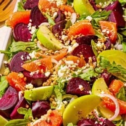 Beet salad on a serving platter next to wooden serving utensils.