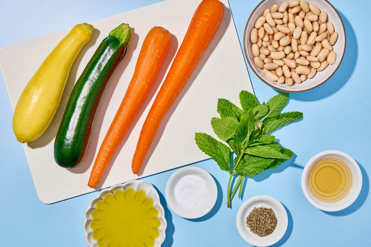 Ingredients for zucchini ribbon salad including zucchini, summer squash, carrots, cannellini beans, mint, vinegar, olive oil, salt and black pepper.
