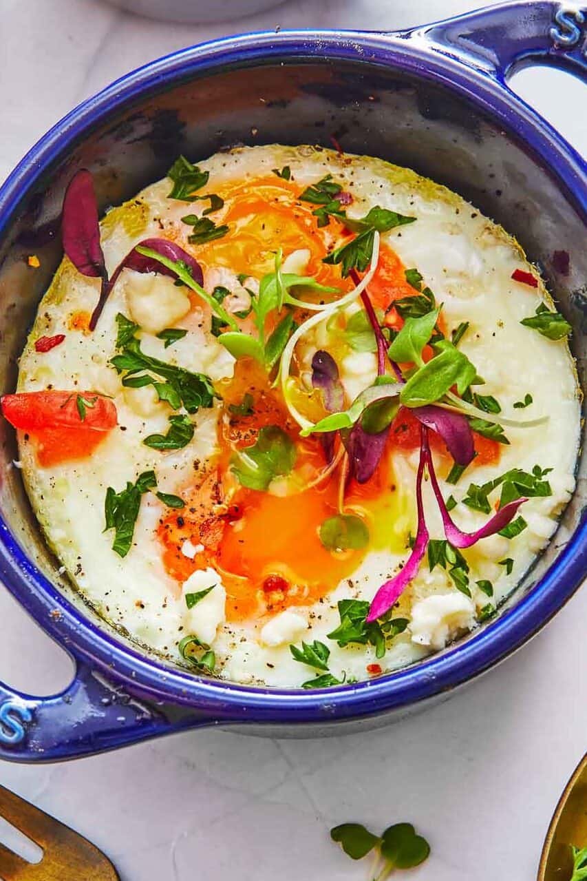 cooked baked eggs in a small baking dish next to a fork.