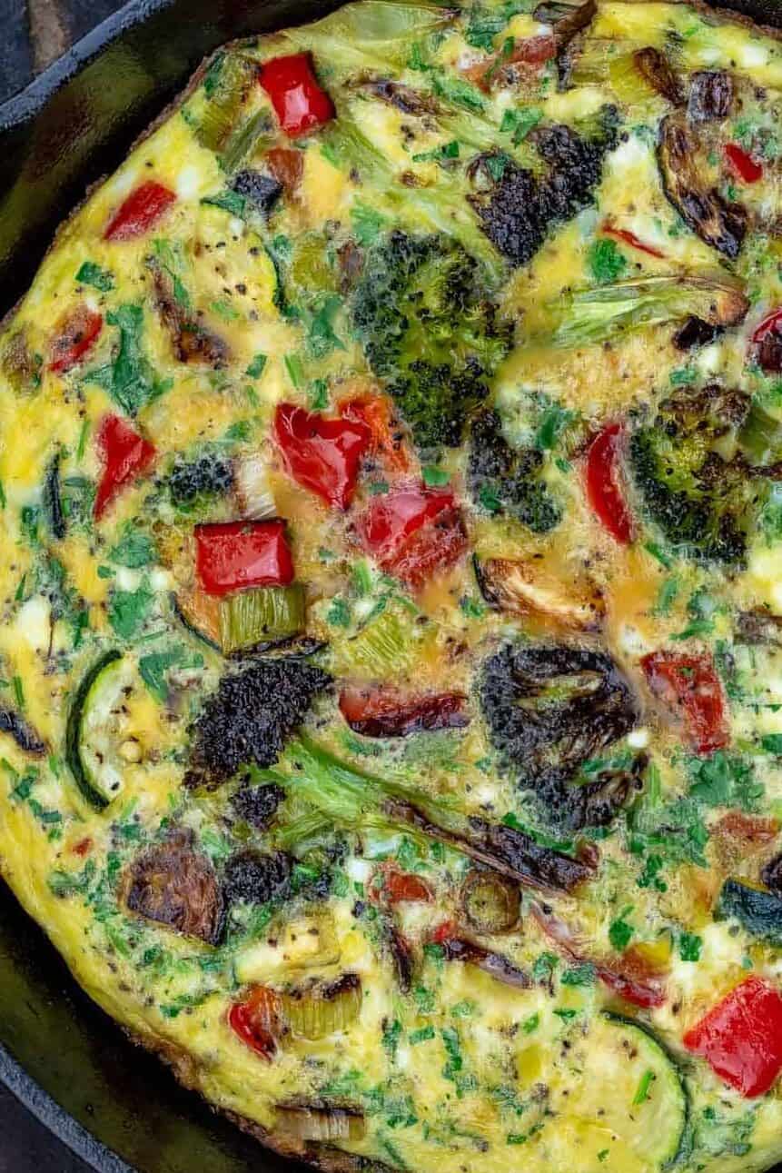 A Vegetable Frittata in a Round, Black Pan on Top of a Wooden Table.
