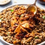 A close up of the red chermoula being spooned onto a serving of the chicken chermoula on a plate.