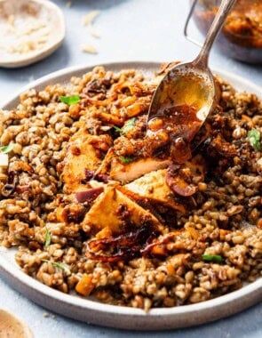 A close up of the red chermoula being spooned onto a serving of the chicken chermoula on a plate.