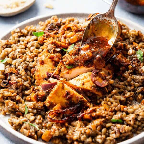 A close up of the red chermoula being spooned onto a serving of the chicken chermoula on a plate.